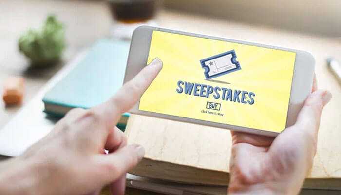 Setting up for success - tycoonstory | tycoonstory media Hand holding a smartphone displaying a sweepstakes entry screen, representing participation and winning sweepstakes engagement.