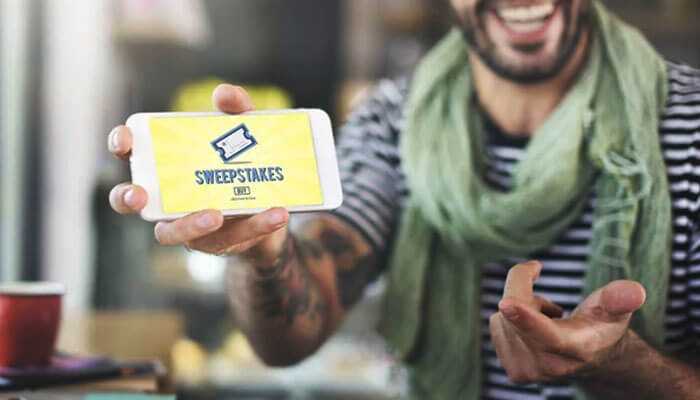 Staying organized and enjoying the journey - tycoonstory | tycoonstory media Man holding a smartphone showing a sweepstakes screen, symbolizing excitement about entering and winning sweepstakes.