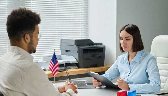 Top recruitment agencies in usa for fast hiring - tycoonstory | tycoonstory media A professional consultation in the office, representing recruitment agencies in usa, with an american flag on the desk.
