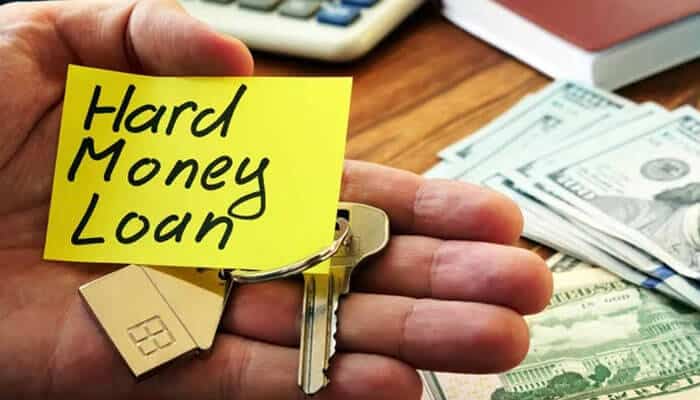 When should you consider a hard money loan - tycoonstory | tycoonstory media A hand holding house keys and a hard money loans note, with cash and a calculator in the background, symbolizing financing.