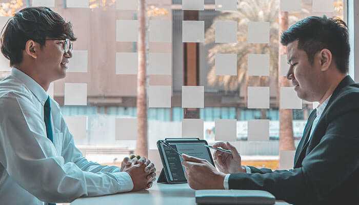 Can you provide me with samples of your assignments - tycoonstory | tycoonstory media Two professionals discussing a document related to online assignment help during a formal meeting