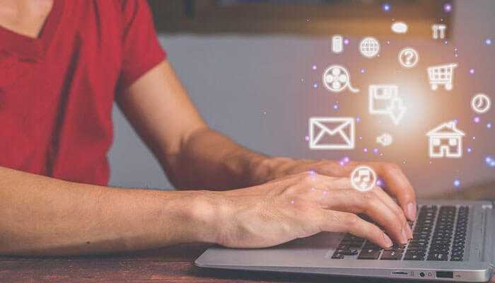 Digital online presence - tycoonstory | tycoonstory media A person in a red shirt is typing on a laptop, with glowing digital icons like an email, shopping cart, and house floating above, symbolizing various online activities, ideal for small business owners.