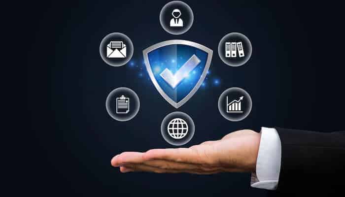 Ensuring security and compliance - tycoonstory | tycoonstory media A hand presents a digital shield with a checkmark, symbolizing it infrastructure management, surrounded by icons for security, data, email, analytics, and connectivity.