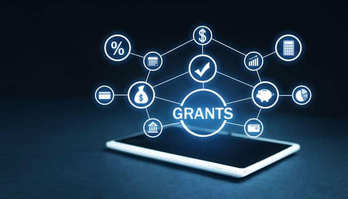Grants and their benefits - tycoonstory | tycoonstory media Financial relief options: a hologram of'GRANTS' with dollar signs and charts floating above a tablet, symbolizing digital funding opportunities