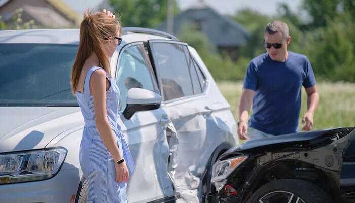 Learn from the experience - tycoonstory | tycoonstory media Two people inspecting vehicle damage in the first moments after a car accident showing a dented white suv and black car.