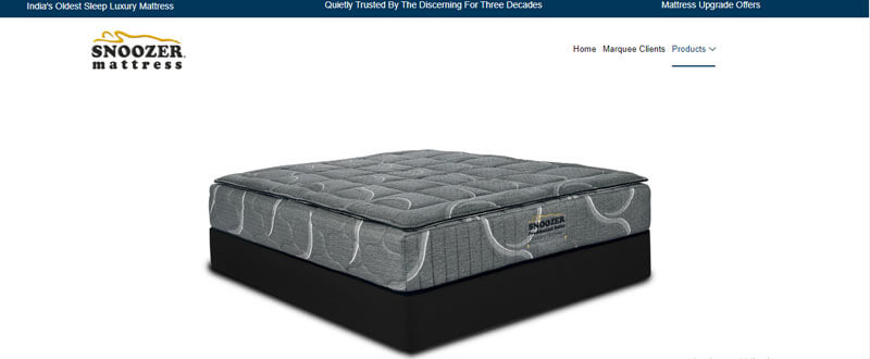 Luxury redefined - tycoonstory | tycoonstory media The image shows a snoozer mattress with a gray quilted design and black base, accompanied by text highlighting it as indias oldest sleep luxury mattress trusted for three decades