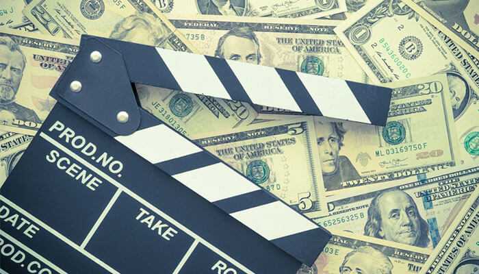 Money | tycoonstory media Millie bobby brown net worth: a film clapperboard on dollar bills represents her financial success from acting and business ventures.
