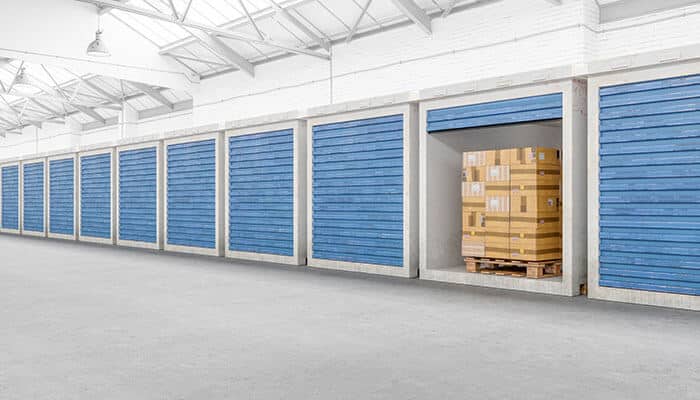 More security - tycoonstory | tycoonstory media Private storage containers with blue roll-up doors, one unit open revealing stacked boxes on a pallet