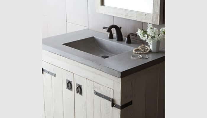 Not checking faucet compatibility - tycoonstory 2 | tycoonstory media A rustic bathroom sink with a concrete countertop, black faucet, wooden vanity, and matching framed mirror, enhanced by simple decor—a perfect choice when buying a bathroom sink.
