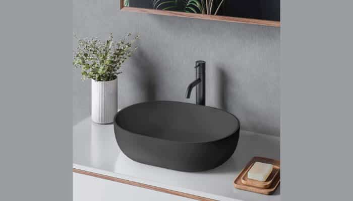 Not taking the bathroom layout into account- tycoonstory | tycoonstory media Buying a bathroom sink: a simple black vessel sink with a minimalist faucet on a white countertop, accompanied by a plant and soap tray to give it that modern feel.