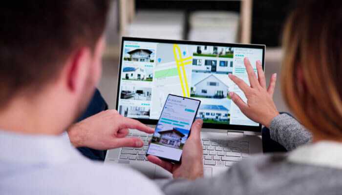 Pamphlets- tycoonstory | tycoonstory media Real estate brochure design: two people explore real estate listings using a laptop and smartphone, highlighting a modern, digital approach to property searching and decision-making.