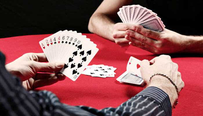 Rummy cards - tycoonstory | tycoonstory media Players holding cards around a table while playing a competitive rummy card game.