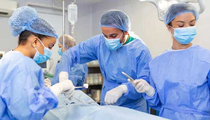 A surgical team in blue scrubs works in a bright room, highlighting liposuction myths.
