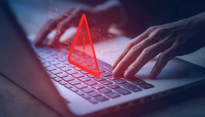 Threads | tycoonstory media Ai and ml solutions in cybersecurity a person typing on a laptop with a red warning icon and exclamation mark symbolize a cybersecurity threat or vulnerability.