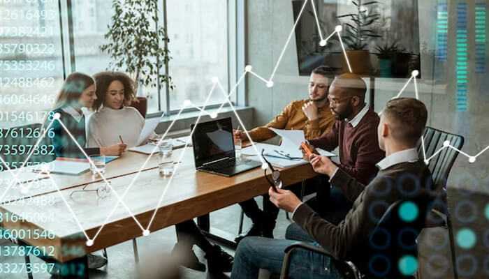 A fresh perspective - tycoonstory | tycoonstory media A diverse team collaborates in a modern office, with financial charts overlaying the scene, symbolizing business strategy and outsourcing for your business.