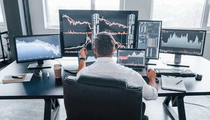 Adapting to market conditions in real time - tycoonstory | tycoonstory media Futures prop trader analyzing real-time market data on multiple screens in a professional trading setup