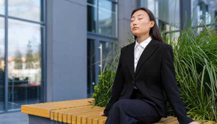 Mindful breathing - tycoonstory | tycoonstory media A women in black suit sitting on a bench and thinking about mindful practices for entrepreneurs