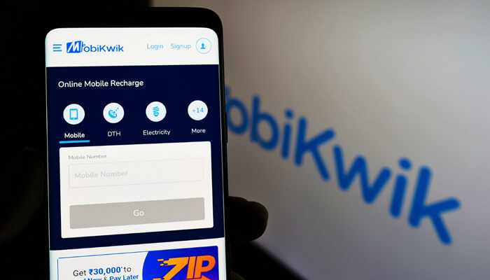 Mobikwik tycoonstory 1 | tycoonstory media A person holding a smartphone displaying the mobikwik app interface for online mobile recharge and upi bill payments.