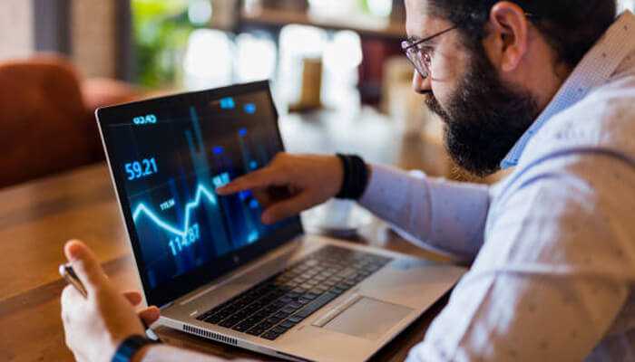 Selecting the right dividend stocks - tycoonstory | tycoonstory media Man analyzing stock market data on a laptop screen, pointing at the rising dividend yield chart.