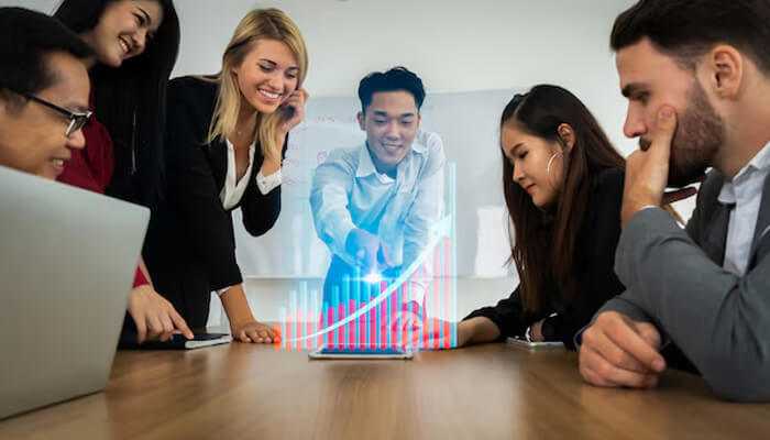 Teams growth - tycoonstory | tycoonstory media Improve your business in 2025 – a team collaborating around a digital tablet displaying a rising growth chart, symbolizing business success and innovation.
