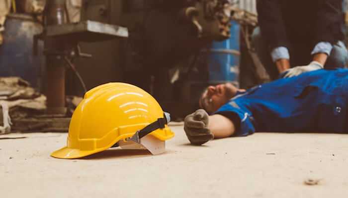Workplace accidents - tycoonstory | tycoonstory media Injured worker lying on the ground with a fallen hard hat, representing workplace accidents—one of the types of personal injury cases