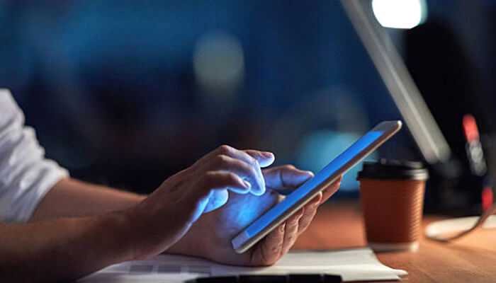 Hinge features tycoonstory 1 | tycoonstory media A person using a tablet in a dimly lit workspace, with a blue screen glow reflecting on their hands, symbolizing digital communication and read receipts.