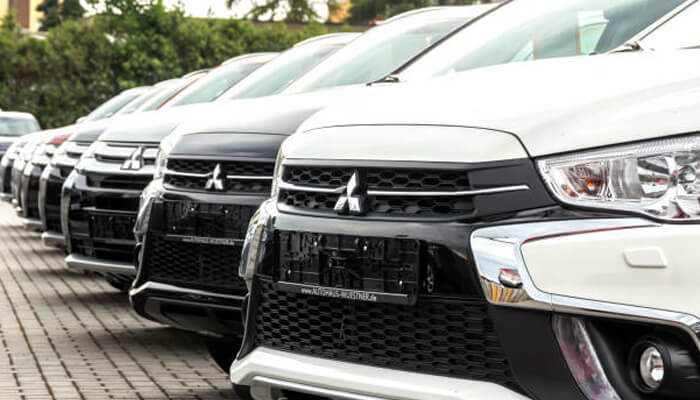 How is driving a four-wheel drive vehicle different than driving one without it - tycoonstory | tycoonstory media Row of mitsubishi four-wheel drive vehicles parked in a dealership lot, showcasing their rugged front grilles and sleek design.