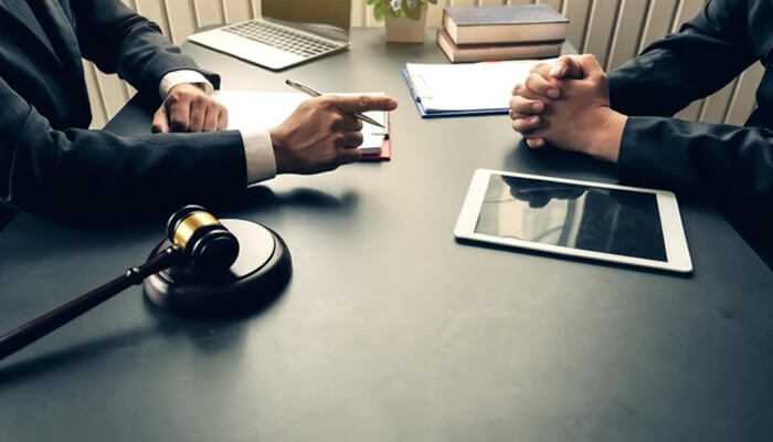 How negligence can lead to harm Two professionals in a legal meeting with a gavel and tablet, discussing workplace negligence and employer liability claims.