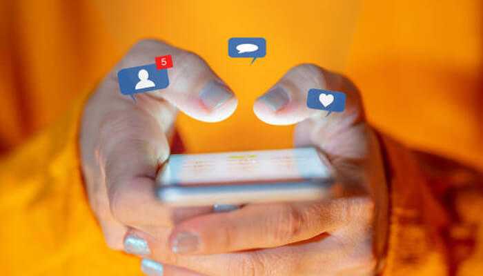 Instagram reels tycoonstory 1 | tycoonstory media Close-up of hands using a smartphone with notification icons floating above, symbolizing engagement and interactions to increase instagram reel reach