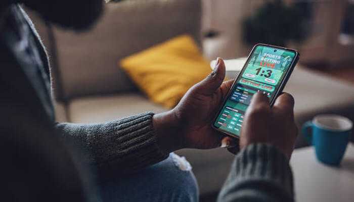 Losers - tycoonstory | tycoonstory media A man focused on playing a game on his smartphone, representing africa's Betting Boom in the gaming industry.