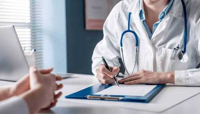 S | tycoonstory media Doctor consulting a patient in a medical office, reviewing paperwork related to medical health insurance coverage.