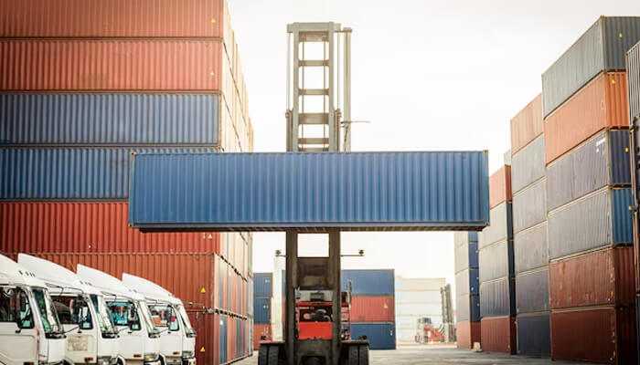 Shipping containers - tycoonstory | tycoonstory media Forklift moving large shipping container at an industrial logistics facility, representing container handling services at right storage depot.