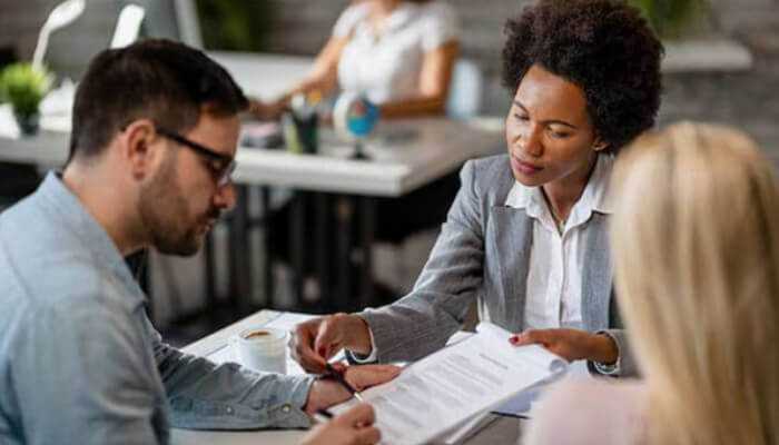 When do you need a consumer loan - tycoonstory | tycoonstory media A financial advisor discussing consumer loans with a couple, reviewing loan documents in a professional office setting.