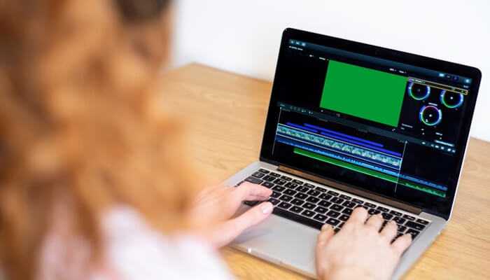 Who can benefit from ai video frame interpolation Person editing a video on a laptop with focus on video frame interpolation and motion smoothing, working on improving video playback and visual quality in the editing software.