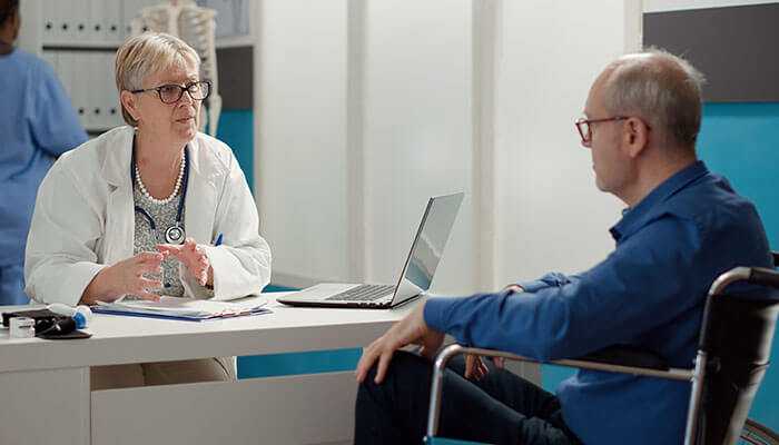 Addressing disabilities and chronic illnesses - tycoonstory | tycoonstory media A doctor discussing treatment options with a patient in a wheelchair, focusing on the management of chronic diseases and viruses, emphasizing the need for medical support.