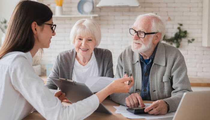 Addressing investor concerns | tycoonstory media Elderly couple discussing financial planning with custodians, reviewing documents at a table.