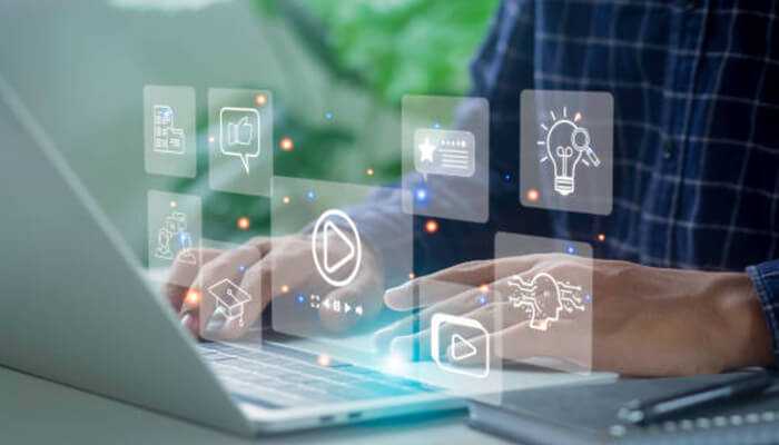 Benefits of custom web design -tycoonstory 1 | tycoonstory media Person working on a laptop with digital interface icons, representing the benefits of custom web design for interactive and modern websites.
