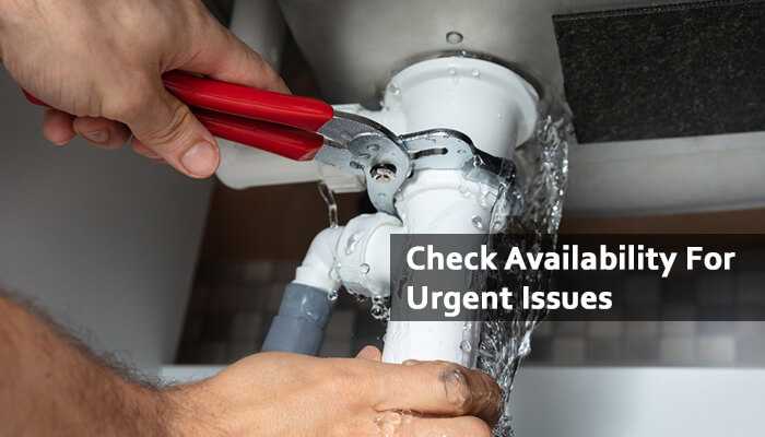 Check availability for urgent issues | tycoonstory media Knoxville plumber using a wrench to fix a leaking pipe under a sink, emphasizing emergency plumbing services and urgent repair availability