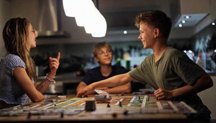 Choose the best games to win real money | tycoonstory media Group of teenagers playing a strategy board game at home, showcasing gaming skills in a fun environment that could translate into real cash winning opportunities.