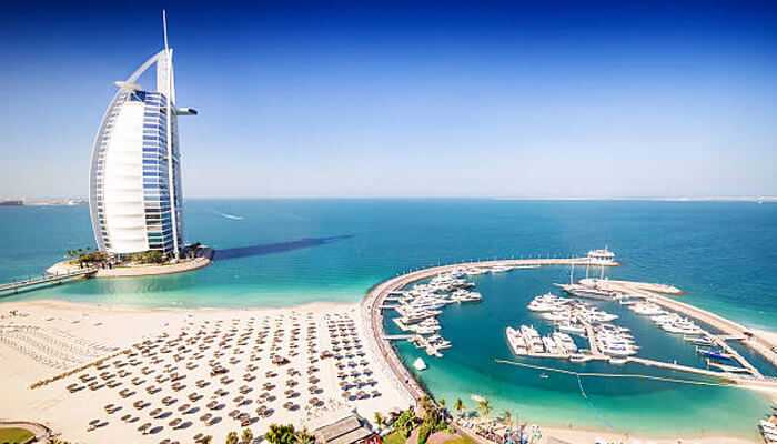 Environmental challenges and adaptation | tycoonstory media Beautiful view of a luxury beach resort in dubai, showcasing the iconic burj al arab and a pristine coastline, representing a prime destination for saudi arabia tourists seeking luxurious beach vacations.