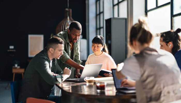 European startups | tycoonstory media A diverse team of european startup founders collaborating on a laptop in a modern office.