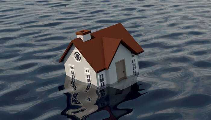 Flood or earthquake damage is covered by default - tycoonstory | tycoonstory media A house partially submerged in floodwater, representing natural disaster risks and widespread home insurance myths about flood damage coverage.