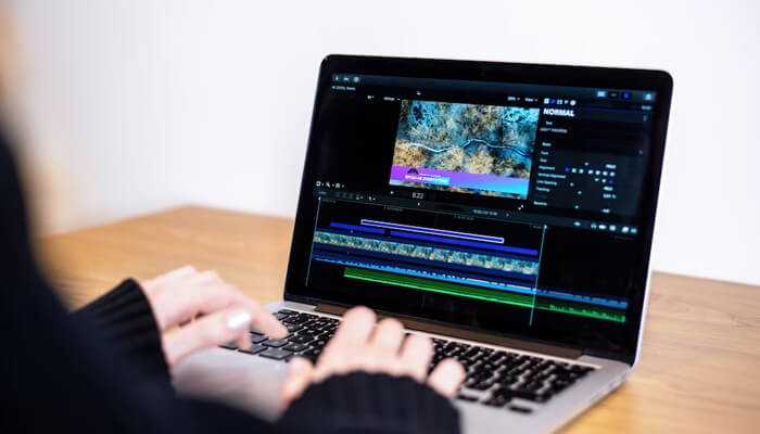 Gd | tycoonstory media Person editing video on a laptop screen using timeline and tools – explaining video file format and video editing process.