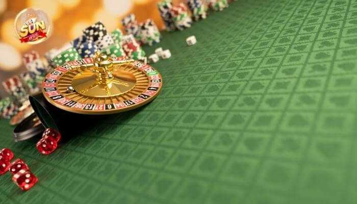 Gfdh | tycoonstory media A casino roulette wheel on a green gaming table with dice and poker chips in the background, featuring the sunwin logo in the corner.