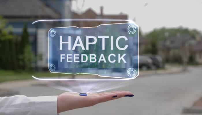 Integrating haptic feedback into wearable development | tycoonstory media A hand displaying a hologram with the words haptic feedback illustrating the futuristic technology in wearables.