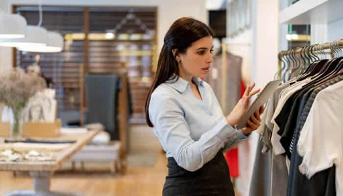 Inventory | tycoonstory media A businesswoman in a retail store using a tablet to manage inventory, reflecting how traditional businesses integrate marketplaces to optimize sales and customer experience.