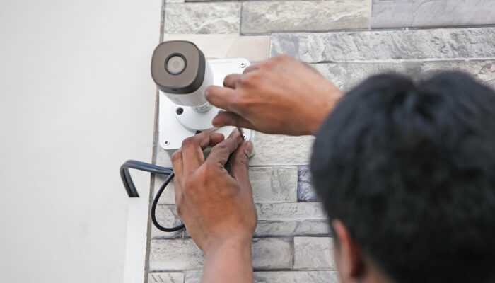 Iss | tycoonstory media A technician installing a security camera system for enhanced surveillance in a small business.
