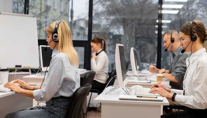 Key features that fuel business growth Call center employees wearing headsets and working at computers, utilizing business call center software to handle customer interactions efficiently in a modern office environment.