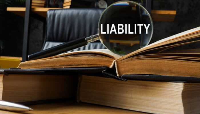 Liability lessons that build market value | tycoonstory media Liability management highlighted through a magnifying glass over the word'LIABILITY' on open books, symbolizing its importance in business decision-making.