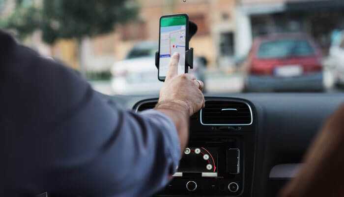 Make smarter decisions with clear data - tycoonstory | tycoonstory media A driver using a smartphone mounted on a car dashboard displaying gps navigation, showing real-time route guidance supported by fleet tracking systems.